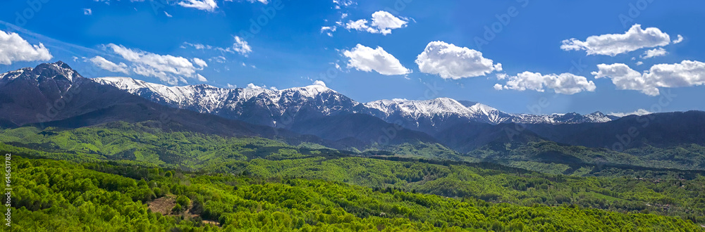 panoramic view from a drone of the mountain with snow peaks and green hills.