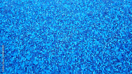 The bottom of a swimming pool made of multi-colored tiles under a layer of water