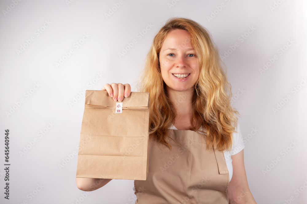 Young woman waiter holding paper bag, fast food delivery, breakfast order, recyclable packaging Young woman waiter holding paper bag, fast food delivery, breakfast order, recyclable packaging