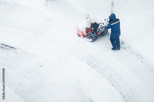 snowblower removes snow, a man cleans the yard outside photo