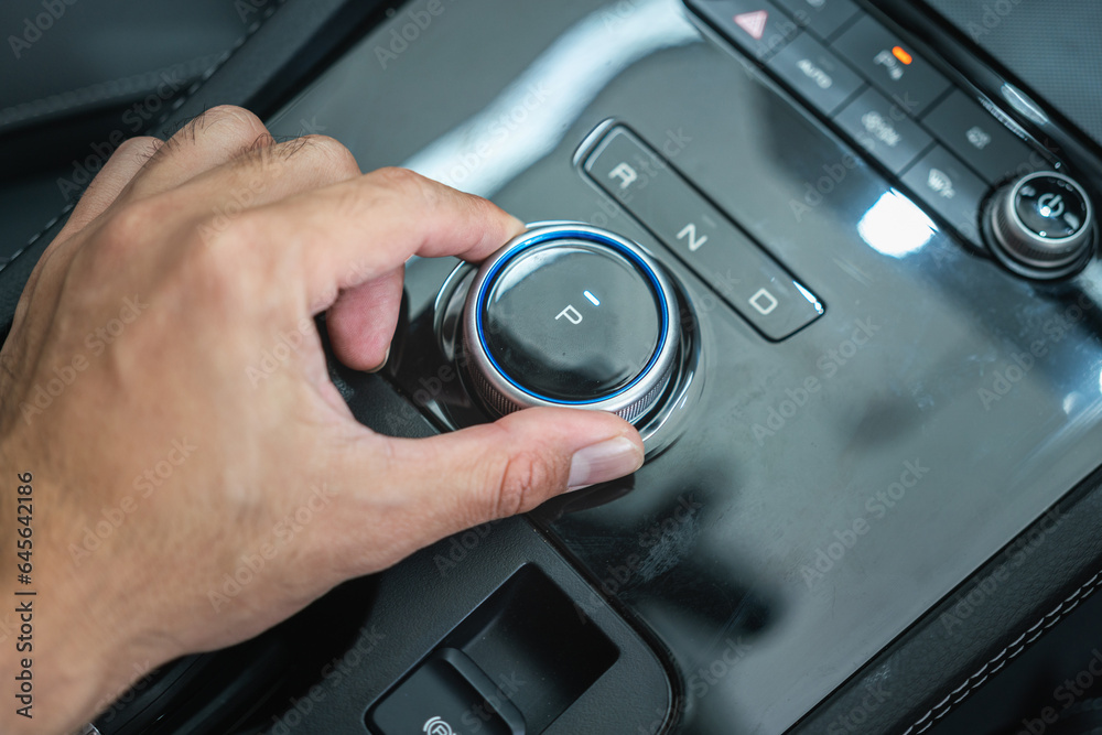 Action of the car driver is shifting the electrical gear to Parking position. Close-uo and selective focus. Action of the car driver is shifting the electrical gear to Parking position. Close-uo and selective focus.