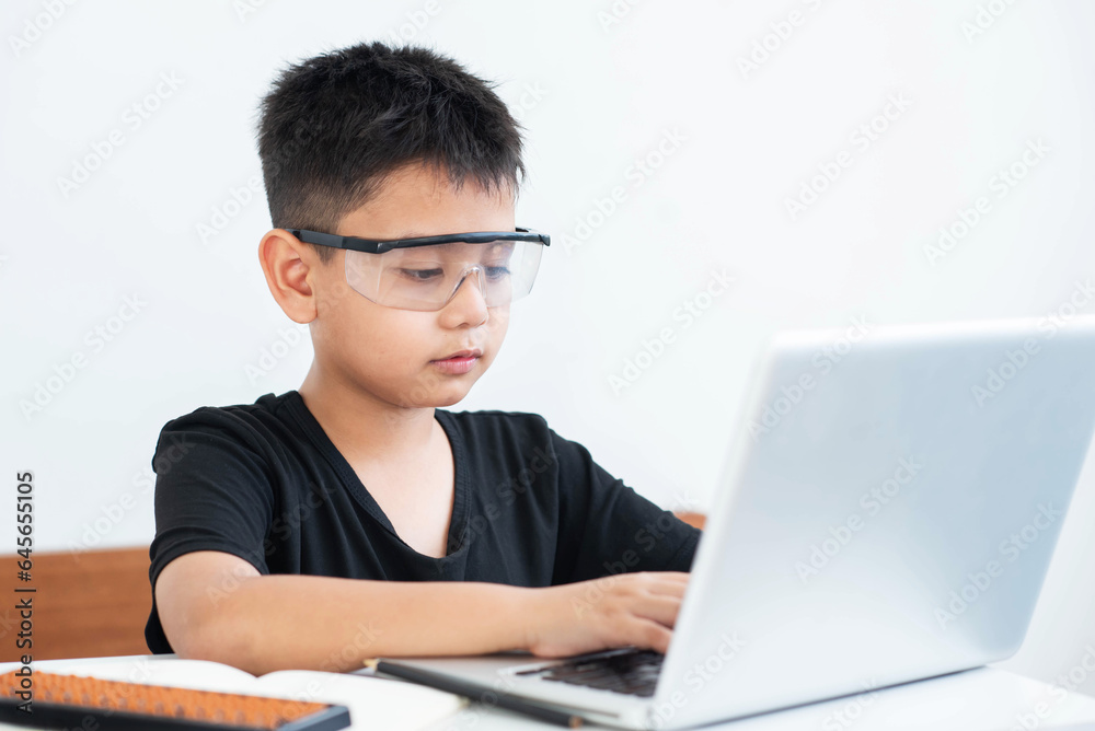 Little Asian boy student using computer laptop learning, virtual internet online class from school teacher. Homeschooling and education concept. Presenting a modern educational way of life. Little Asian boy student using computer laptop learning, virtual internet online class from school teacher. Homeschooling and education concept. Presenting a modern educational way of life.