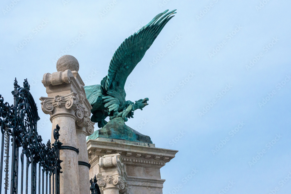 Bronze statue eagle, of the mythological bird Turul on the gate of Buda Palace against the blue sky.