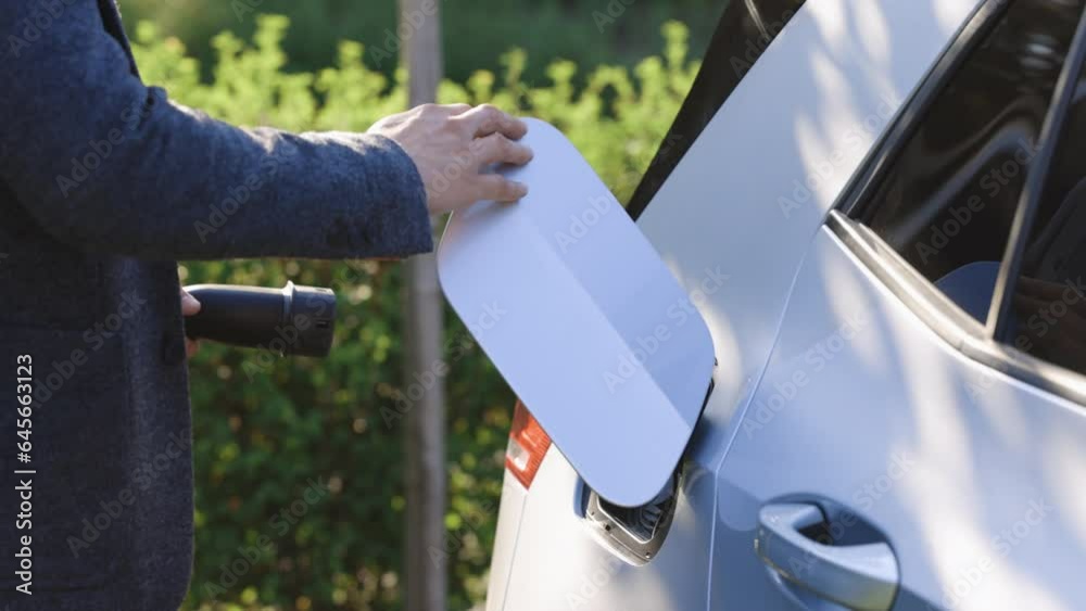 Unrecognizable businessman unplugging electric car. Luxury electrical car full. Electrical power filling compete and cable disconnected. Save ecology alternative energy sustainable of future Unrecognizable businessman unplugging electric car. Luxury electrical car full. Electrical power filling compete and cable disconnected. Save ecology alternative energy sustainable of future
