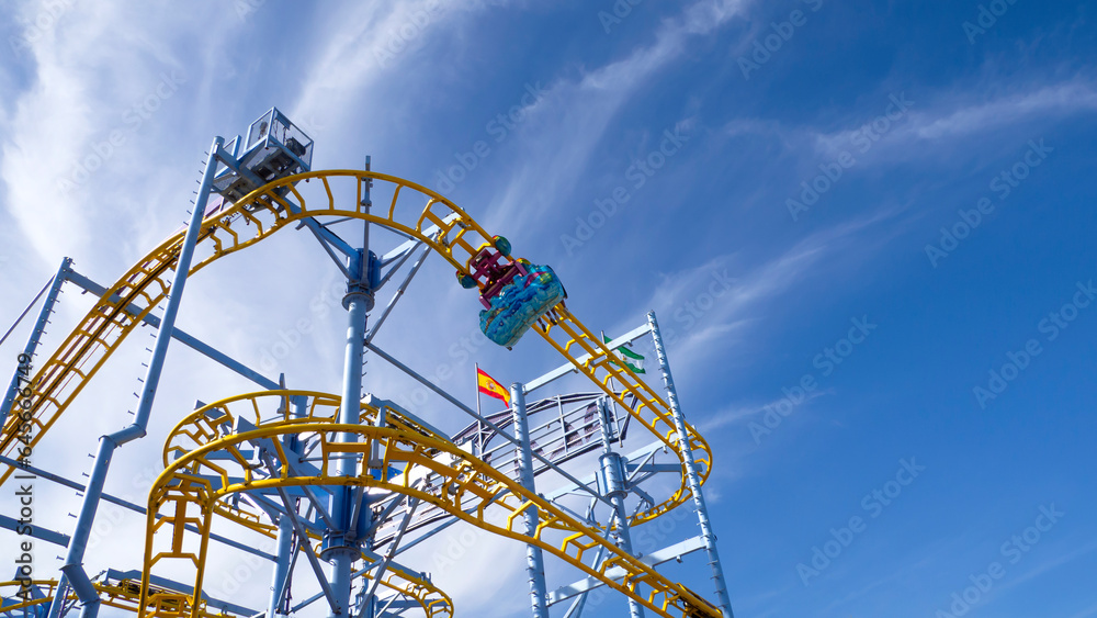 A roller coaster ride on a blue sky background at a fair in Spain .