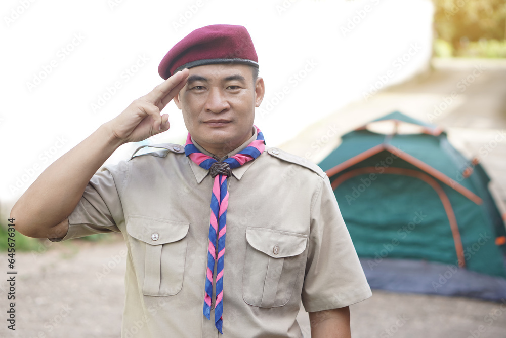 Handsome Asian man wear boy scout uniform, red cap, blue and pink striped scarf, make hand sign symbol, isolated on white background. Concept, educational career with uniform in school, Thailand. Handsome Asian man wear boy scout uniform, red cap, blue and pink striped scarf, make hand sign symbol, isolated on white background. Concept, educational career with uniform in school, Thailand.