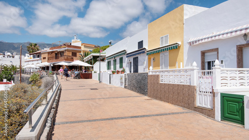 Boardwalk along the seafront lined with traditional homes now converted into fish and seafood restaurants visited by tourists and locals alike in La Caleta, Tenerife, Canary Islands, Spain photo