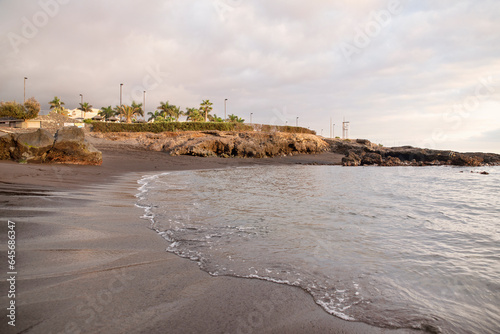 Cloudy afternoon over a secluded beach with black volcanic sand known as Playa la Jaquita, near the small town of Alcala located in the Municipality of Gua de Isora, Tenerife, Canary Islands, Spain photo