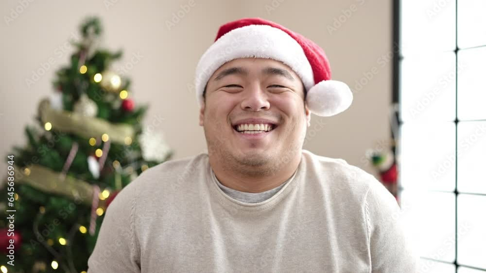 Young chinese man smiling confident standing by christmas tree at home Young chinese man smiling confident standing by christmas tree at home