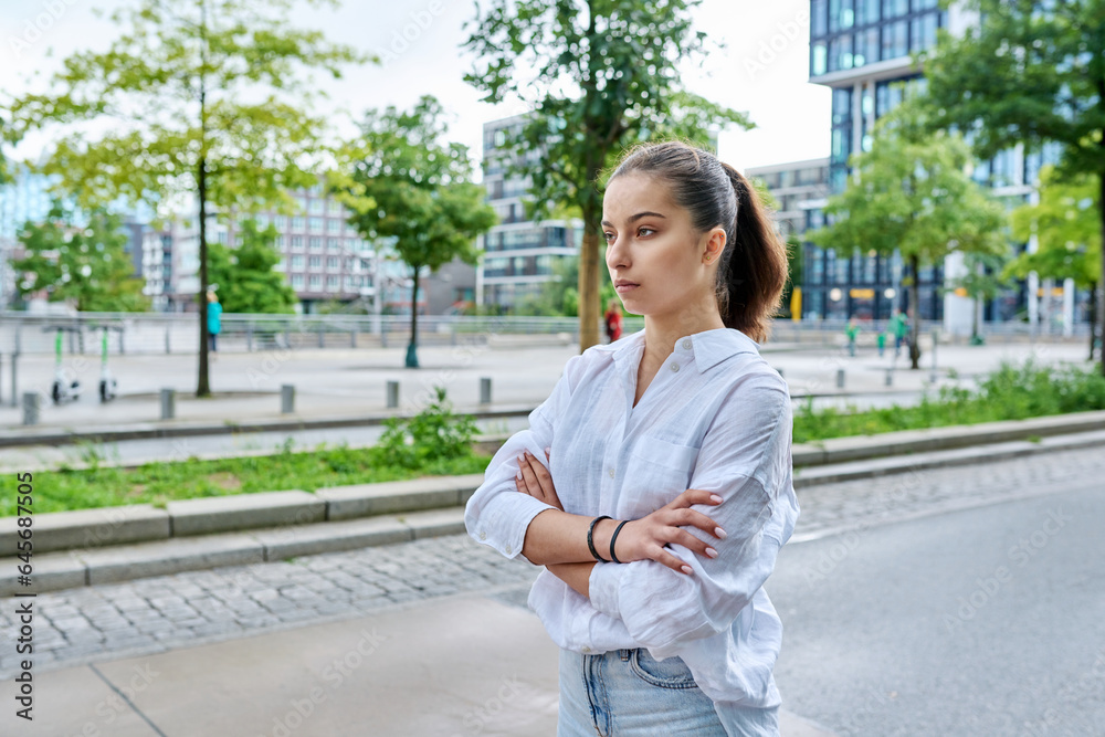 Serious confident teenage girl looking forward, outdoor on city street Serious confident teenage girl looking forward, outdoor on city street