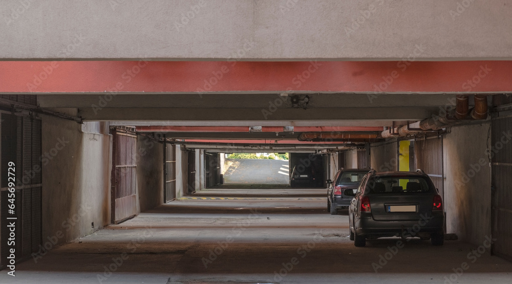 Stary garaż podziemny w stylu vintage. Widoczne zaparkowane samochody na korytarzu.