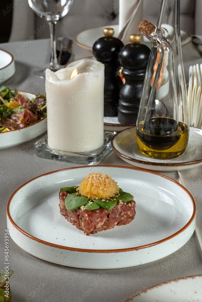 Fresh beef tartar dish with tasty vegetables. Garnished with lettuce leaves. Vertical photo