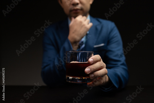 Man with glass of whiskey, businessman drinking whiskey in dark room, drinking alcohol drunk, businessman stress. Intoxicated drink concept.