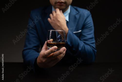 Man with glass of whiskey, businessman drinking whiskey in dark room, drinking alcohol drunk, businessman stress. Intoxicated drink concept.