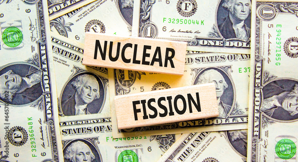 Nuclear fission symbol. Concept words Nuclear fission on beautiful wooden blocks. Dollar bills. Beautiful background from dollar bills. Business science nuclear fission concept. Copy space.