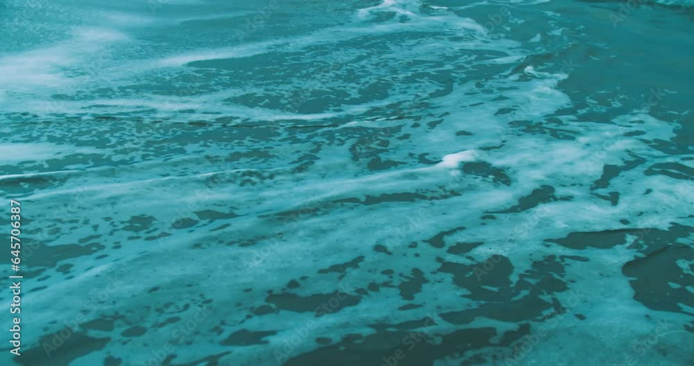 Waves of sea rolling to the sandy beach. Close-up shot of calming foamy water Waves of sea rolling to the sandy beach. Close-up shot of calming foamy water