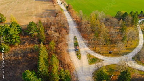 Dynamic video of countryside in north america at fall. Aerial view of unusual road between trees and farm fields in fall Come to north america to enjoy view of fall golden trees, beautiful farm fields