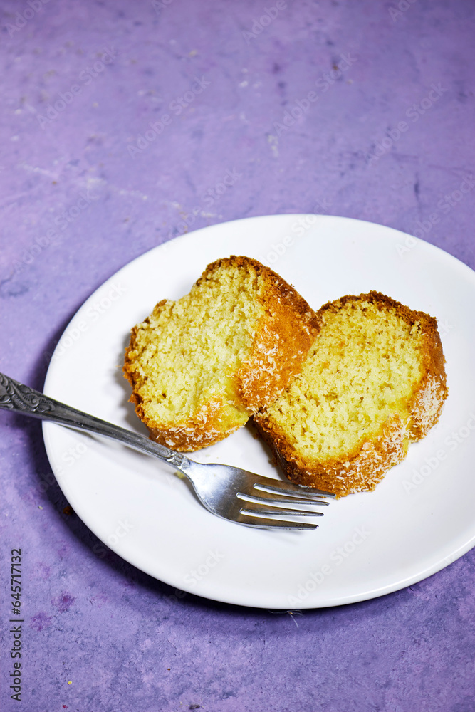 slice of delicious coconut bundt cake in white plate isolated on purple background slice of delicious coconut bundt cake in white plate isolated on purple background