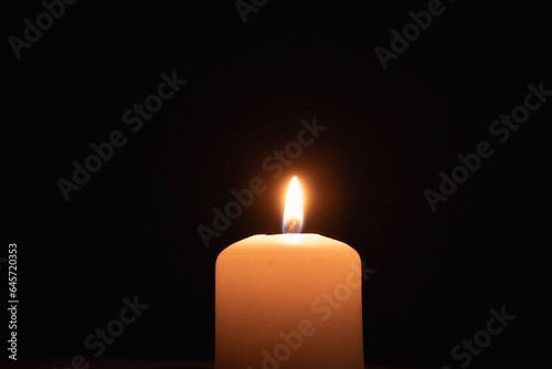 A memorial candle on a dark background. Burning candle on black background, copy space