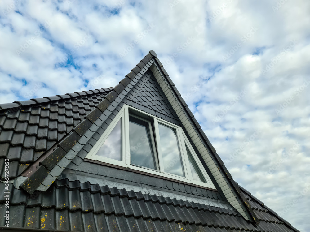 Open roof window in velux style with black roof tiles.