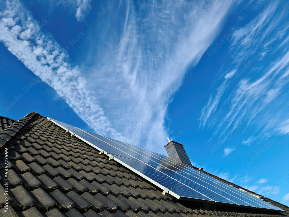 Solar panels producing clean energy on a roof of a residential house - obrazy, fototapety, plakaty 