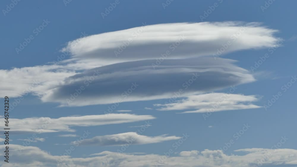Blue sky with moving Lenticular clouds, Lenticularis lentil-shaped during Foehn wind - real time. Topics: weather phenomenon, meteorology, science, climate, nature, season Blue sky with moving Lenticular clouds, Lenticularis lentil-shaped during Foehn wind - real time. Topics: weather phenomenon, meteorology, science, climate, nature, season