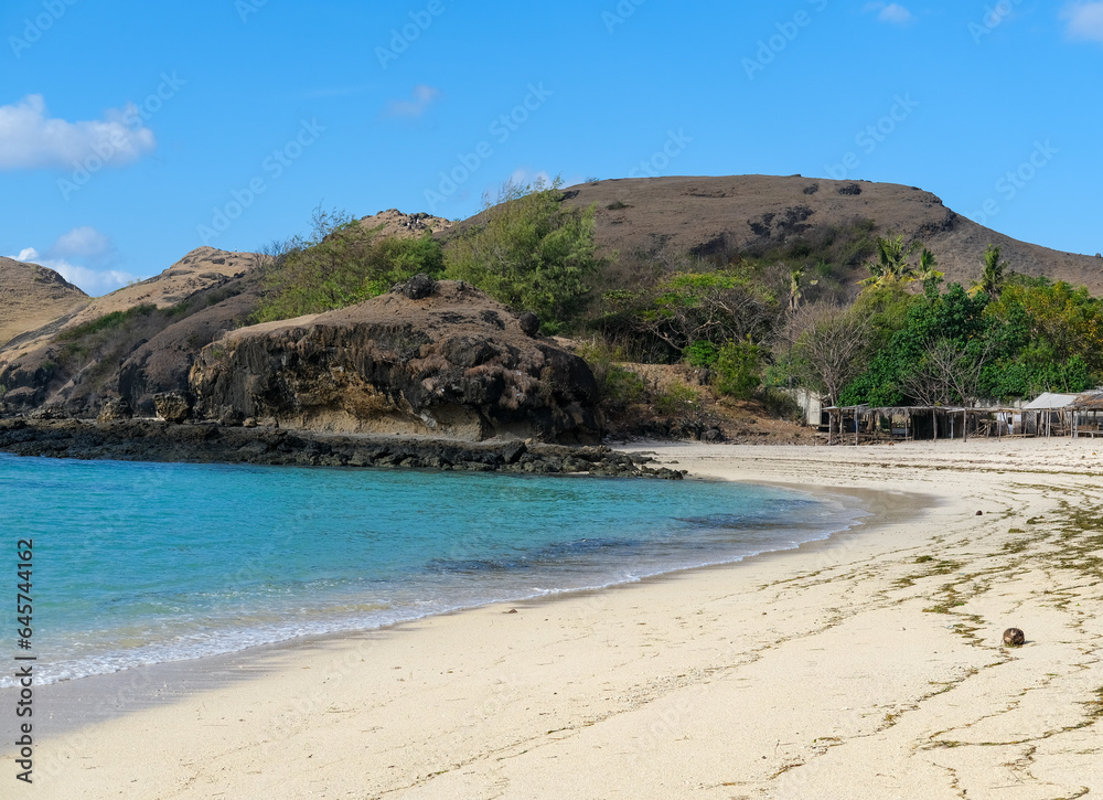 Kuta beach Lombok. Kuta Lombok is a small spread-out town in a beautiful bay lined by a long white sand beach, a beach with blue sky, a beach with sky and white sand, view of the beach in island