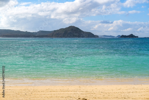 Kuta beach Lombok. Kuta Lombok is a small spread-out town in a beautiful bay lined by a long white sand beach, a beach with blue sky, a beach with sky and white sand, view of the beach in island