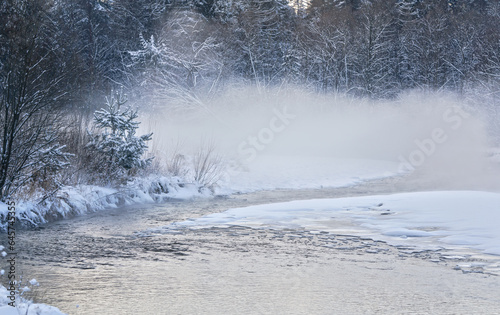Cold winter river, steam visible above water, dark trees on side © Lubo Ivanko