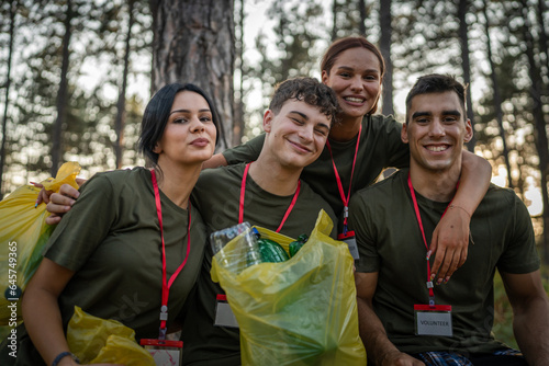 portrait of group of friends volunteers prepare to collect garbage waste and clean forest nature in summer day slow motion