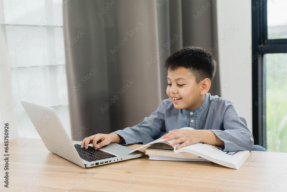 Little Asian boy student using computer laptop learning. Educational concept Social distancing, staying at home, presenting a modern educational way of life. Little Asian boy student using computer laptop learning. Educational concept Social distancing, staying at home, presenting a modern educational way of life.