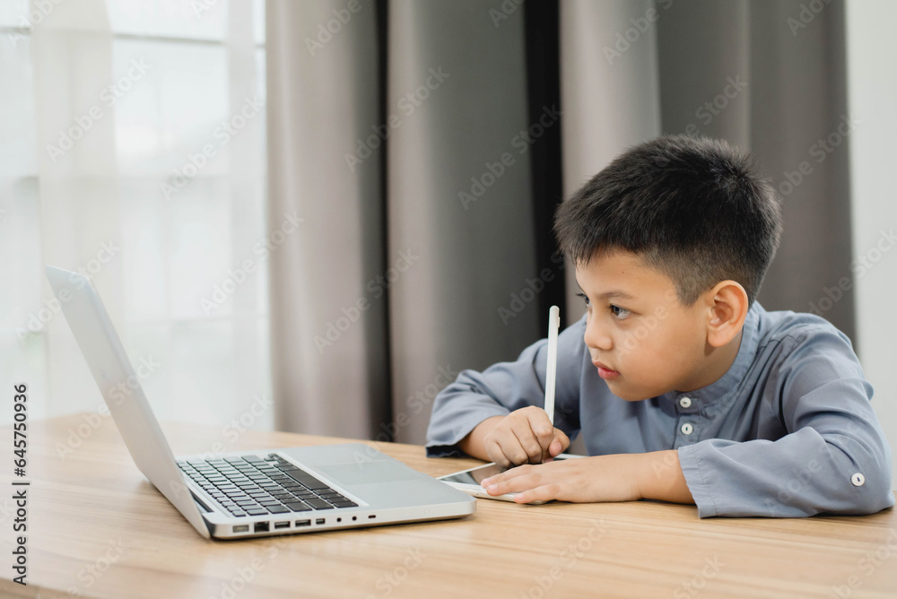 Little Asian boy student using computer laptop and tablet learning. Educational concept Social distancing, staying at home, presenting a modern educational way of life. Little Asian boy student using computer laptop and tablet learning. Educational concept Social distancing, staying at home, presenting a modern educational way of life.