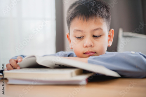 Little Asian boy student reading the books for learning. Educational concept Social distancing, staying at home, presenting a modern educational way of life.