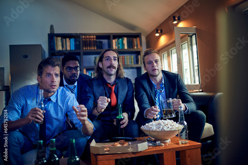 Young and diverse group of businessmen getting nervous during an intense soccer or football match on tv