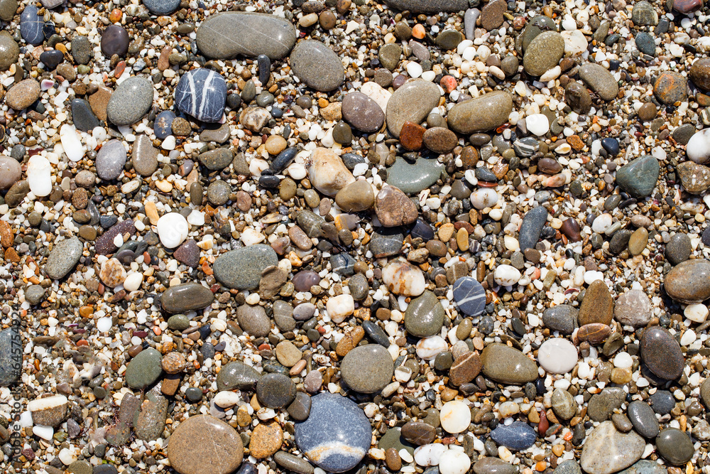 Oval stones on pebble beach, multicolored close-up, glare from the sun Oval stones on pebble beach, multicolored close-up, glare from the sun