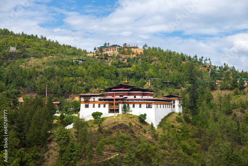 Scenic view of a monastery on a hilltop in Bhutan with mountains in the background