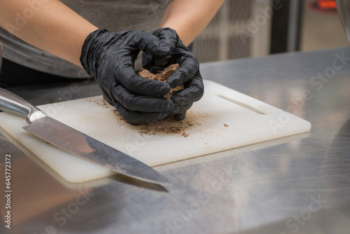 chef cutting sweet chocolate bars with caramel filling , fudge candy for cheesecake preparation photo