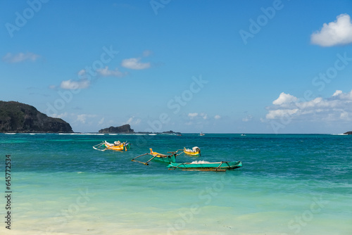 Fototapeta Naklejka Na Ścianę i Meble -  beautiful view at Tanjung Aan beach Lombok, colorful boats on the beach, blue sea and blue sky, kuta mandalika, traditional fishing boat, hidden gem in Lombok