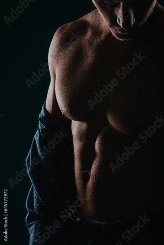 Silhouette photo of fit man showing his abs and chest, focus on chest.