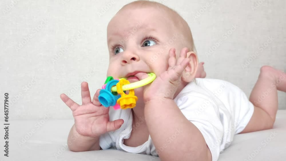 Funny baby laughs and plays with a rattle on a white blanket, baby's morning Funny baby laughs and plays with a rattle on a white blanket, baby's morning