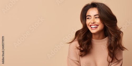 Portrait of a young latin woman with pleasant smile over beige backgroundl with copy space. Beautiful girl in warm sweater