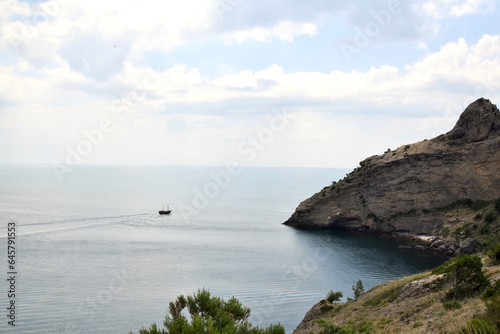 Seascape. A pleasure boat sails on the sea against the background of a rocky coast 