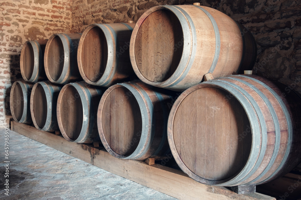Row of oak barrels in a dry cool dark wine cellar in basement