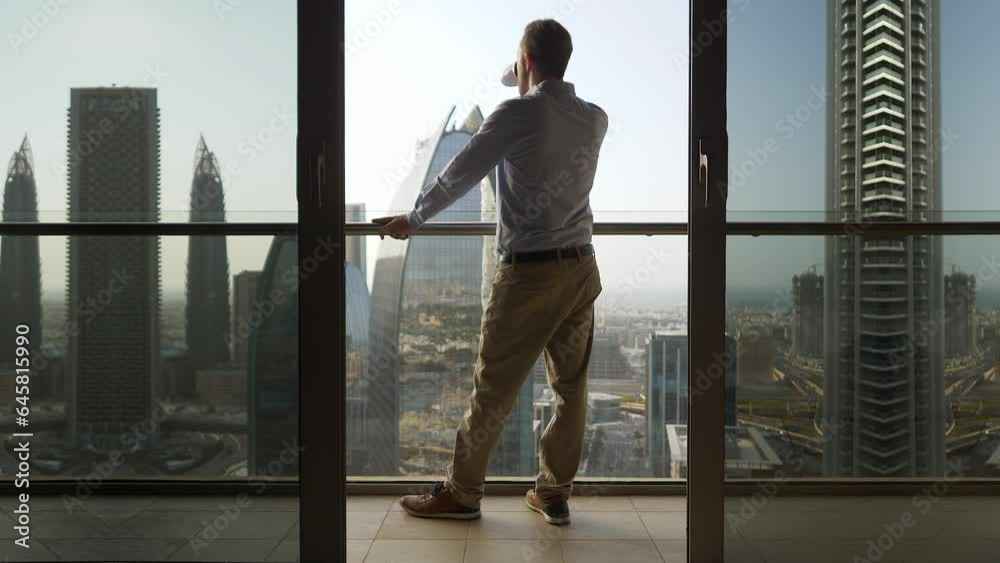 Young Man Succeed In High Rise Apartment Looking at Urban Buildings Young Man Succeed In High Rise Apartment Looking at Urban Buildings