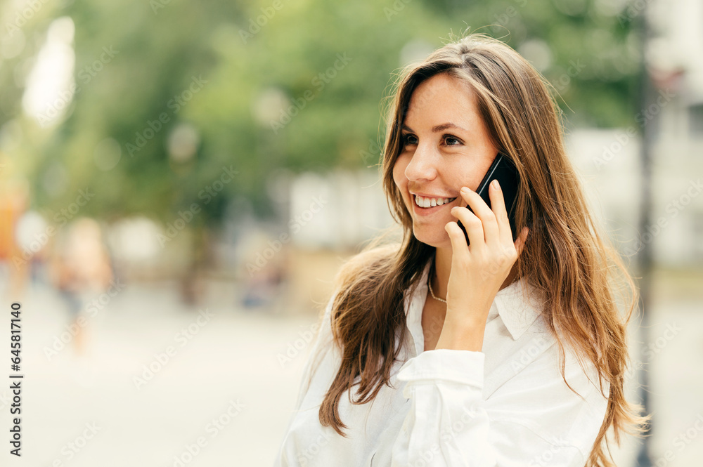 Handsome young business woman is having a conversation over the phone outdoorsin a park. Handsome young business woman is having a conversation over the phone outdoorsin a park.
