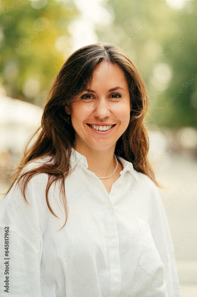 Vertical street portrait of a young smiling woman wearing white shirt over green background. Vertical street portrait of a young smiling woman wearing white shirt over green background.