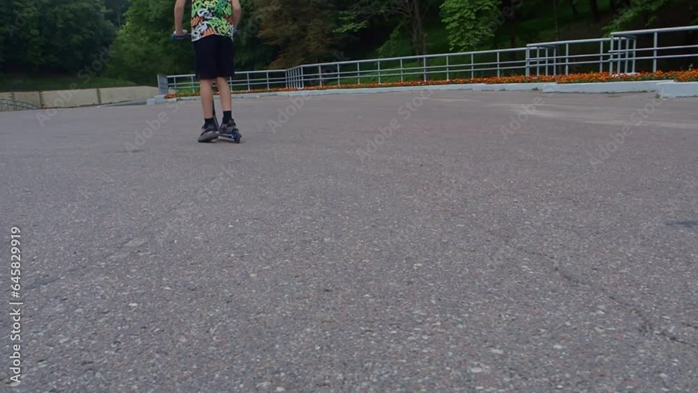 a boy in black shorts, colored sneakers and a girl in gray shorts and a blue T-shirt ride a blue scooter in the summer and do tricks on the asphalt. Children spend their free time 