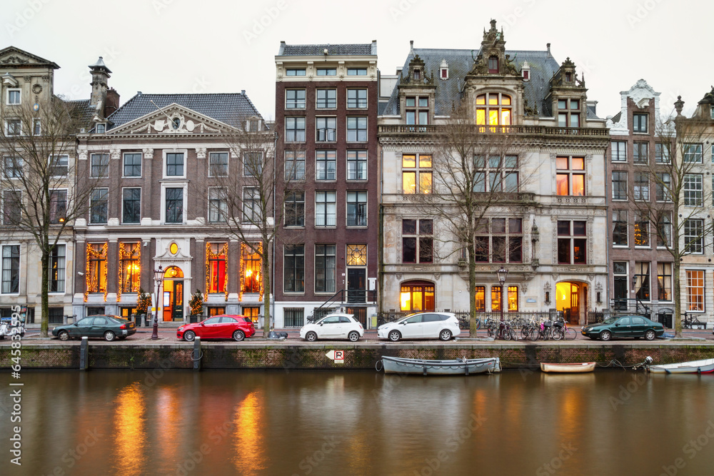 Cityscape - evening view of the houses with festive decorations and the city channel with boats, city of Amsterdam, The Netherlands