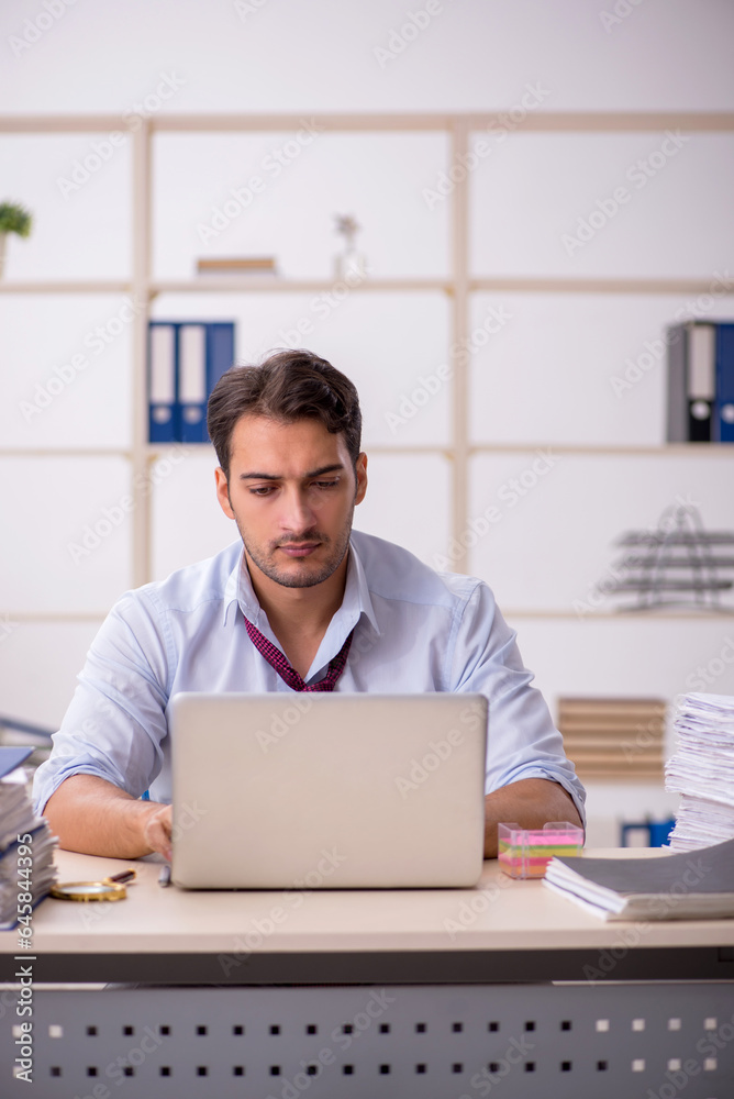 Young male employee and too much work in the office Young male employee and too much work in the office