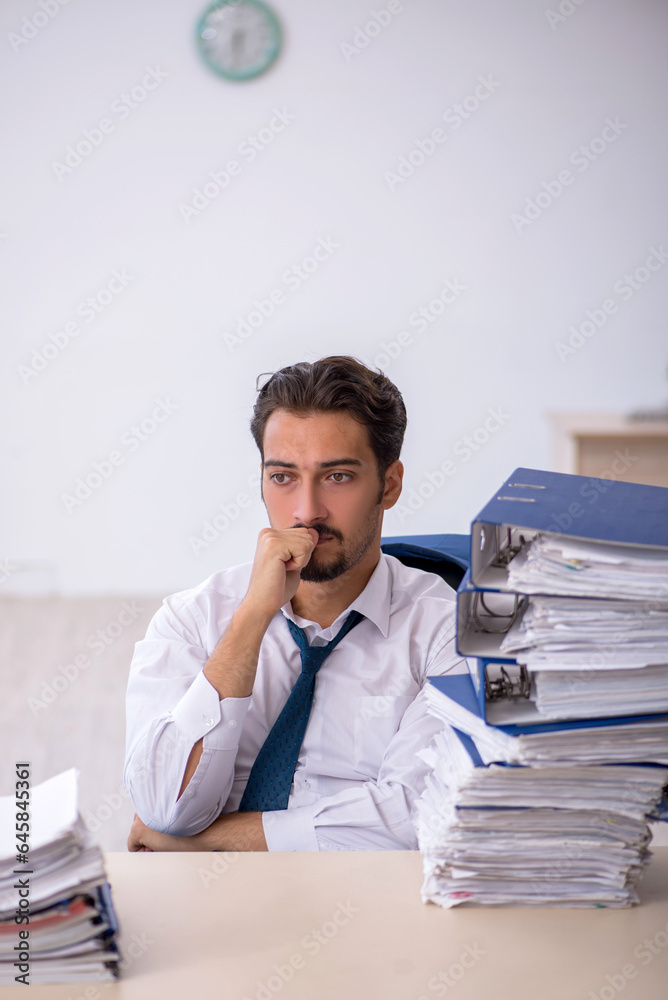 Young male employee and too much work in the office Young male employee and too much work in the office